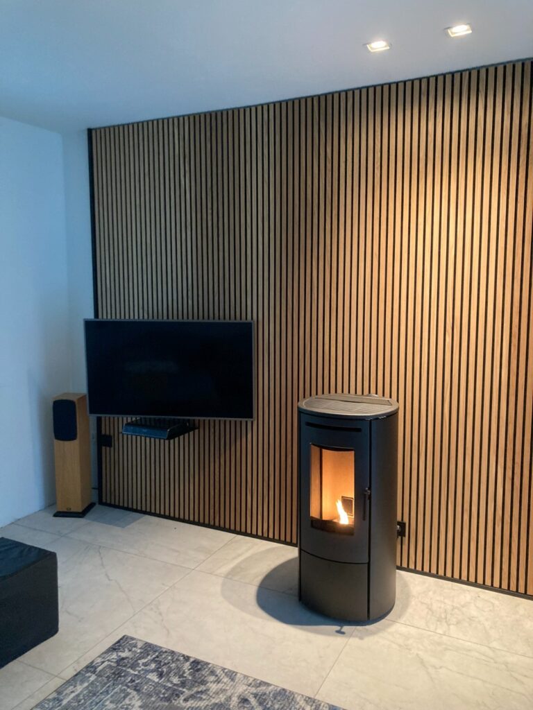 Nordic Fire pelletkachel voor een wand van panelwood met een televisie aan de wand.